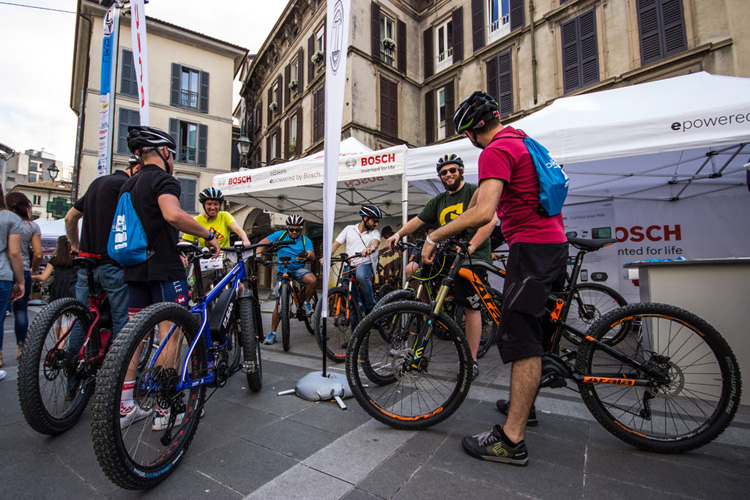 Ciclisti in sella a bici elettriche per le strade di Lecco